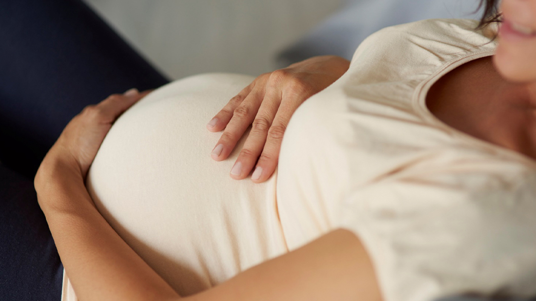 Woman holding her stomach while lying on a sofa