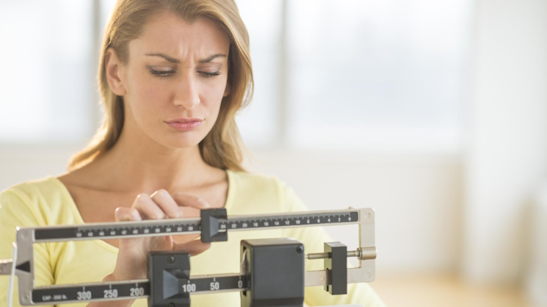 Woman measuring her weight on a scale